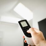 Close-up of a man using a remote to control air conditioning indoors.