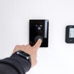 A hand adjusting a digital thermostat in a modern home interior, showcasing smart home technology.