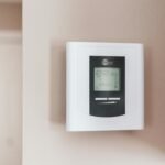 Close-up of a modern digital thermostat mounted on a wall, displaying temperature settings in Celsius.